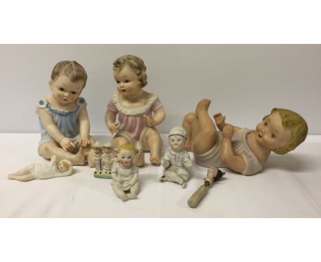 A collection of small bisque baby/piano baby figures and others. 2 have bases marked a blue crown mark with letter A undernea