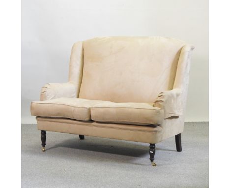 A Wesley Barrell beige suede upholstered two seater sofa, on turned legs and castors, 136cm