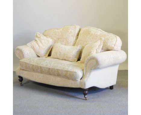 A cream upholstered sofa, on turned legs and castors, 172cm
