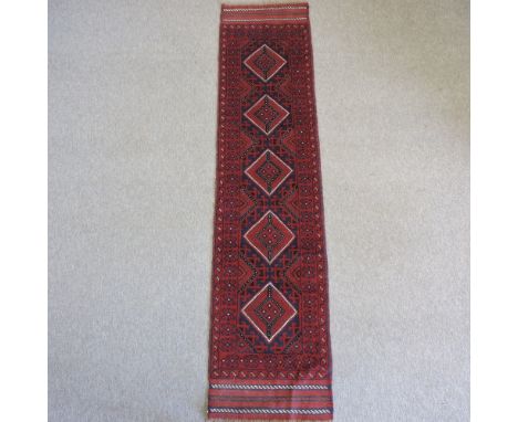 A Persian woollen runner, with geometric design, on a red ground, 258 x 60cm