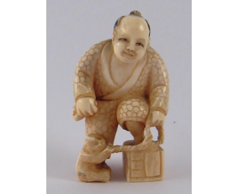 A Japanese ivory netsuke of a man in elaborate robe with cage and monkey on a lead, signed beneath cage. ht.5cm. Circa 1910