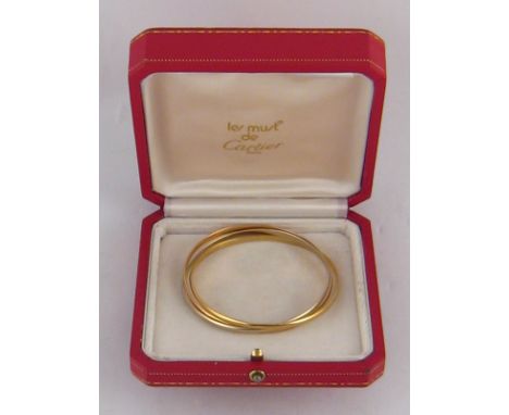 Cartier . A three colour 18 carat gold bangle by Cartier, signed Cartier and numbered 58599, internal diameter approx 62mm, 2