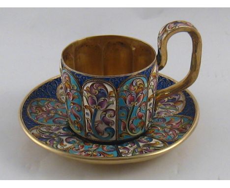 A Russian silver gilt cup and saucer, the cup with embossed vertical panels, both cup and saucer with cloisonne shaded enamel