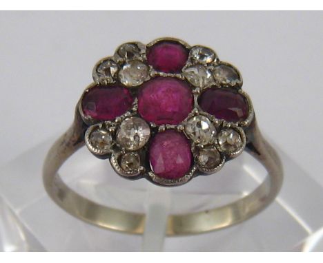 A white metal (tests 18 carat gold) ruby and old brilliant cut diamond cluster ring, the principal ruby measuring approx 4.7 