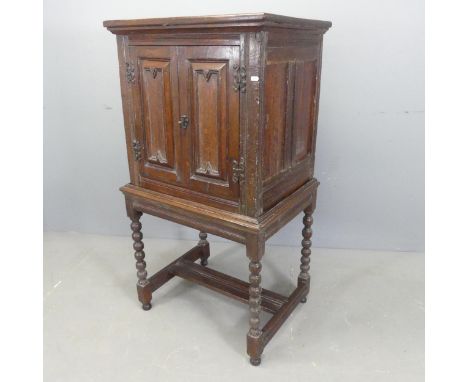 An early 20th century oak Jacobean style cabinet on stand, with two fielded panelled doors, bobbin turned legs and H-shaped s