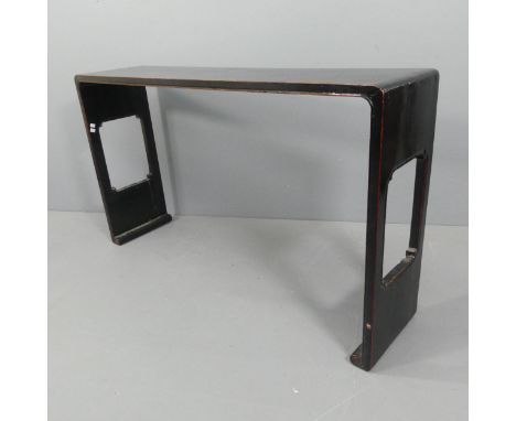 An antique Chinese black lacquered altar table or console table, the curved ended top supported on pierced ends with scroll f