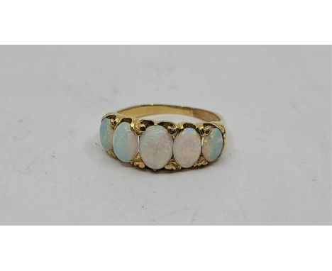 A precious yellow metal five stone opal ring, set five graduated oval cabochon opals (yellow metal assessed as 18ct. gold). (