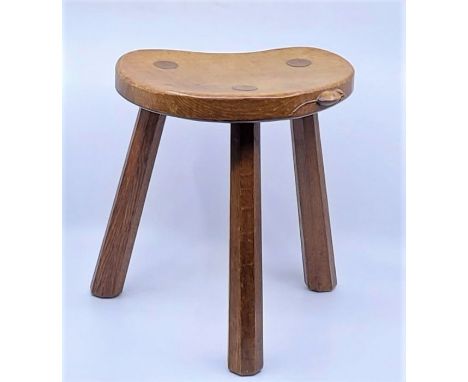 A Robert "Mouseman" Thompson oak three legged stool, the dished kidney shaped seat with carved mouse signature, triple revers