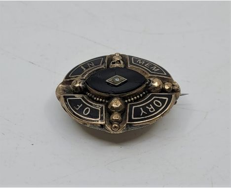 A Victorian gilt metal, black enamel, jet and seed pearl set oval mourning brooch, having raised eliptical jet centre set sin