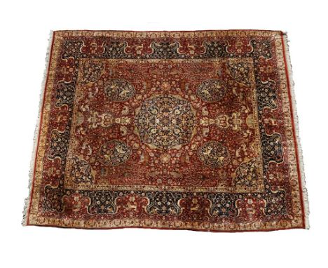 A FINE PERSIAN CARPET of Isfahan design, the central rectangular red ground field worked with a blue and ivory floral medalli