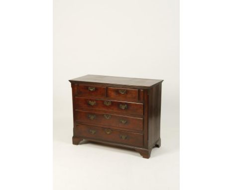 AN OAK CHEST OF DRAWERS with a rectangular top above two short and three long graduated drawers between canted corners, with 