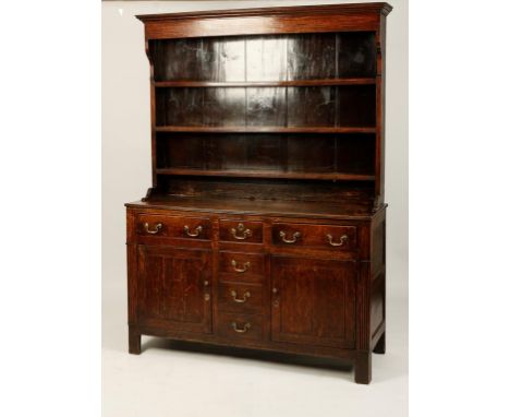AN OAK DRESSER, the upper section with three shelves beneath a moulded cornice and boarded back, the base with a rectangular 