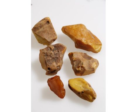 SIX BOULDER LUMPS OF PEBBLE WORN YELLOW-ORANGE OPAQUE AMBER, the largest piece c.9cm long x 5cm wide x 3cm deep, c.271.1g (al