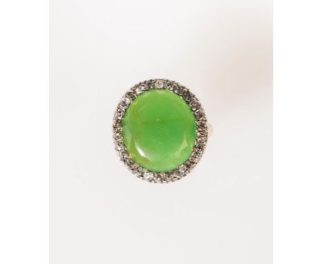 A JADE AND DIAMOND RING, the large, part faceted green jade disc surrounded by an old-cut diamond border, in unmarked white m
