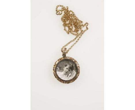 AN UNMARKED YELLOW METAL PHOTO LOCKET PENDANT, with engine turned engraved decoration to one side, the other with circular ph