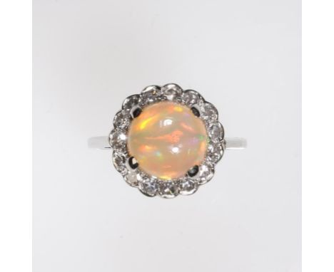 AN OPAL AND DIAMOND CLUSTER RING, the central round cabochon opal of green-yellow tone, in a four claw setting, raised above 