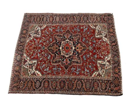 A NORTH WEST PERSIAN HERIZ-TYPE CARPET, the brick red ground rectangular central field worked with a blue, ivory and multi-co