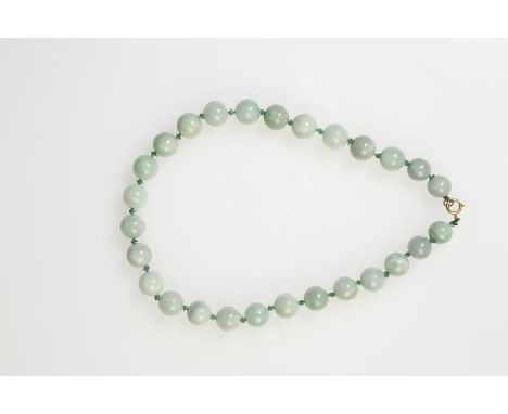 A JADE BEAD NECKLACE, each spherical bead c.11-12mm wide, knotted with a yellow metal jump ring clasp, 38cm long