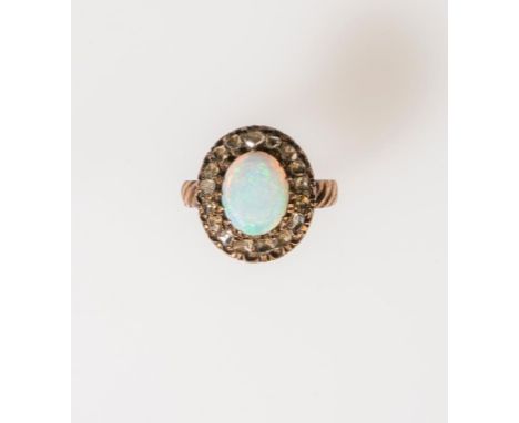 A VICTORIAN OPAL AND ROSE-CUT DIAMOND RING, the central oval cabochon opal claw-set and surrounded by a border of rose-cut di