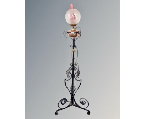 An antique wrought iron rise and fall standard oil lamp with copper reservoir, chimney and shade.
