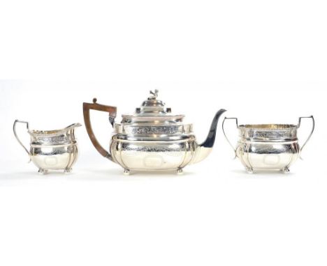 A GEORGE V SILVER THREE PIECE OBLONG TEA SERVICE WITH GADROONED RIM AND ENGRAVED WITH TRAILING FOLIAGE, INTEGRAL HINGE TO TEA