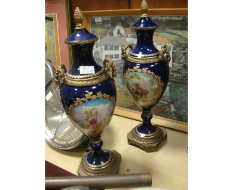 A pair of Edwardian urn vases with brass mounts and acorn finial