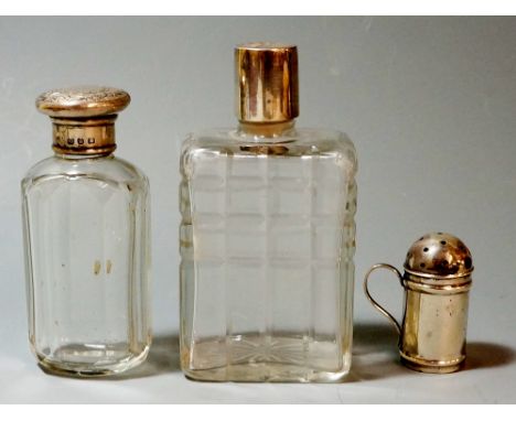 Two silver topped glass scent bottles - the first oval shaped with flat cut glass panel sides, the round foliate engraved sil