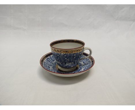 A late 18th Century Worcester (Davis/Flight) tea cup and saucer decorated with blue fruit and scroll panels, gilt borders 