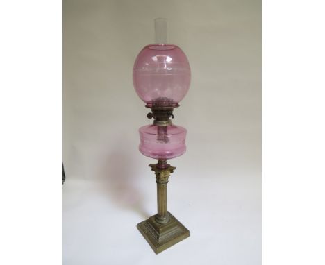 A Victorian oil lamp the etched cranberry shade and reservoir over reeded brass Corinthian column base