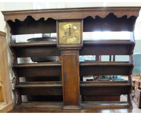 An unusual oak dresser top with four shelves, divided by a brass dial longcase clock movement