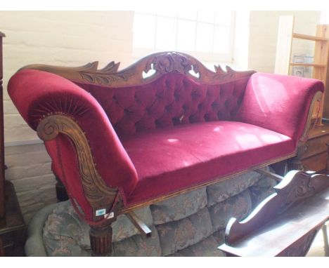 A Victorian mahogany scroll end settee with carved leaf back and maroon button back upholstery on square fluted legs