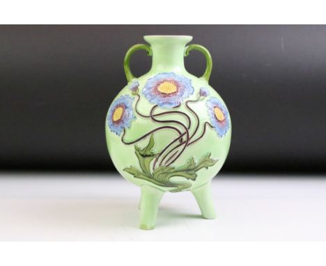 Austrian Art Nouveau majolica twin-handled vase of spherical form, with tubelined floral decoration, raised on three feet, wi