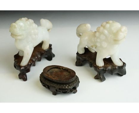 A pair of oriental carved jade lions with fitted wooden stands. 