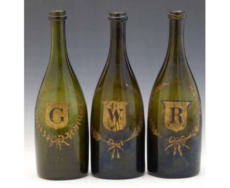 Three green glass bottles, 19th century, gilded with G, W and R each in a wreathed shield, height 29cm (3) Condition report: 