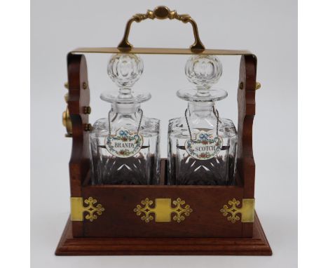 Two decanter locking tantalus (H: 28 cm)with solid mahogany frame, brass fittings and two associated lead crystal cut decante