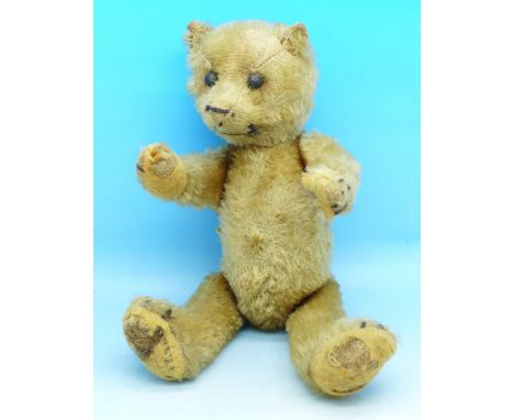 A small straw filled plush Teddy bear, boot button eyes and jointed limbs, pads worn, 24cm