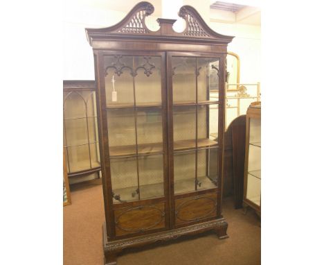 A Chippendale-style mahogany display cabinet, pierced swan-neck pediment above a pair of full-length astragal-glazed doors, l