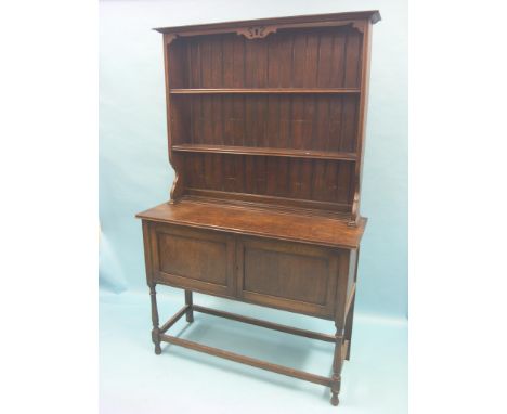 A solid, dark oak dresser, twin-shelf plate rack above panelled cupboard base, on baluster legs, 4ft.  