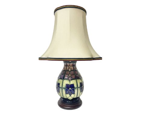 Moorcroft table lamp, of baluster form, decorated in the Violet pattern, on wooden plinth, with accompanying cream shade of l