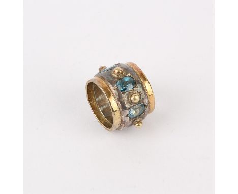 Silver ring by Michael A Bolton, a wide band ring set with three oval cut blue stones, approximate ring size N/O/PCondition R
