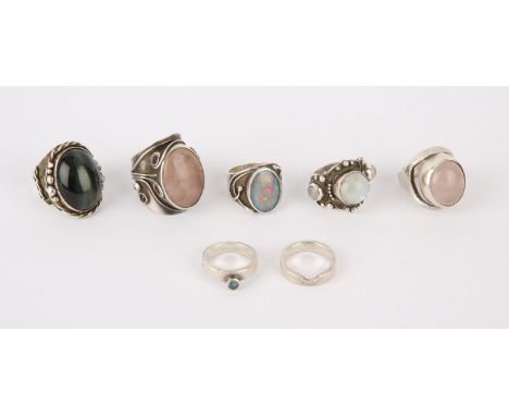Six silver rings, including two set with rose quartz, one set with a moonstone, an interlocking ring, and two othersCondition