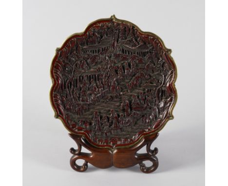 A CHINESE RED LACQUER DISHQianlong seal mark, but 19th century Shaped circular form with gilt-metal cusped rim,decorated with