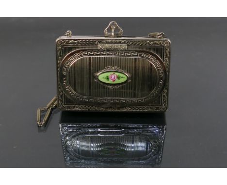 A cocktail purse style powder compact and sovereign holder on a chain. It has an oval opening front panel with an enamel flow