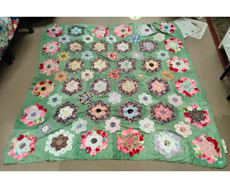 A large patch work quilt (unbacked) with green material with hexagonal pieces in floral shapes, 205x210 cm 