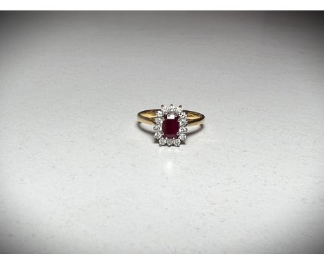 A 18ct hallmarked gold ring set with a central emerald cut ruby surrounded by 14 diamonds. 