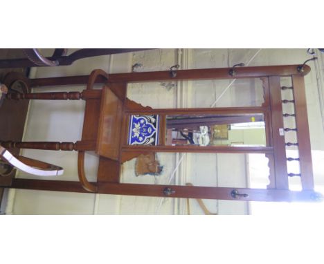 An Edwardian stained wood hall stand with turned spindles, central mirror and tiled panel, the glove box and umbrella stands 