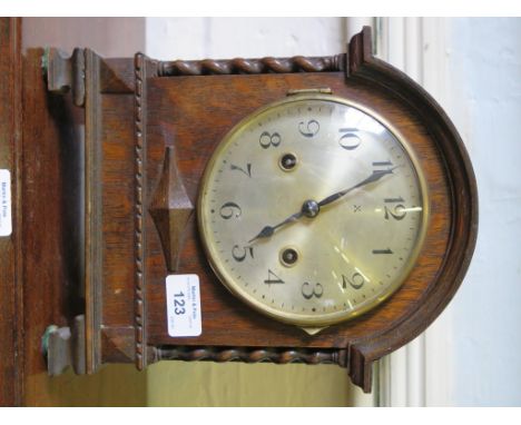 An oak cased mantel clock, the arched case with barley twist supports enclosing a silvered dial, the twin train movement stri