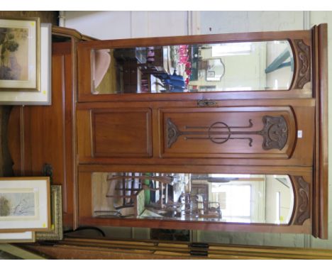 A late Victorian walnut wardrobe, the reduced cornice over a carved panel door flanked by mirrors on a base with one long dra