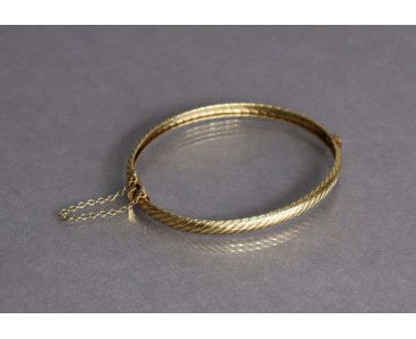 A yellow metal oval stiff hinged bangle of rope-twist design (7.3g).