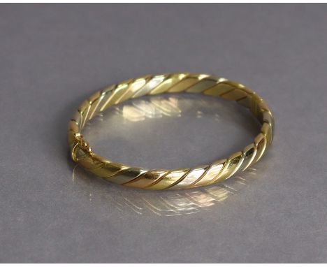 An 18ct three-colour gold stiff hinged bangle of rope-twist design (26.7g).